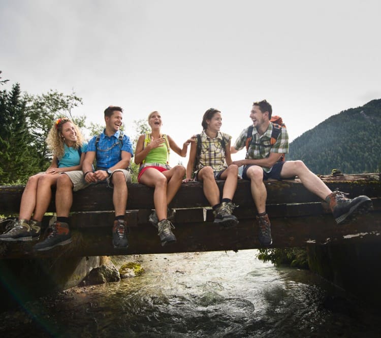 Wanderer sitzen auf der Brücke über einem Bach in Flachau © Flachau Tourismus