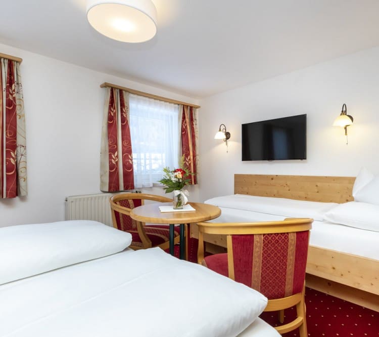 Doppelbett, Einzelbett, TV und Tisch im Dreibettzimmer